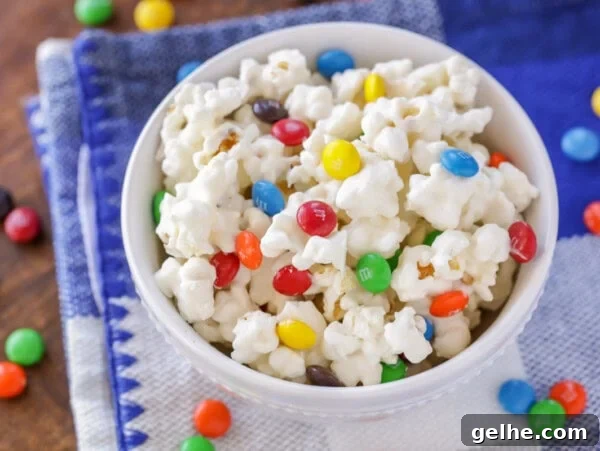 Puppy Chow Popcorn Recipe: Sweet, Crunchy Party Snack 6 White chocolate popcorn with M&Ms in white bowl.