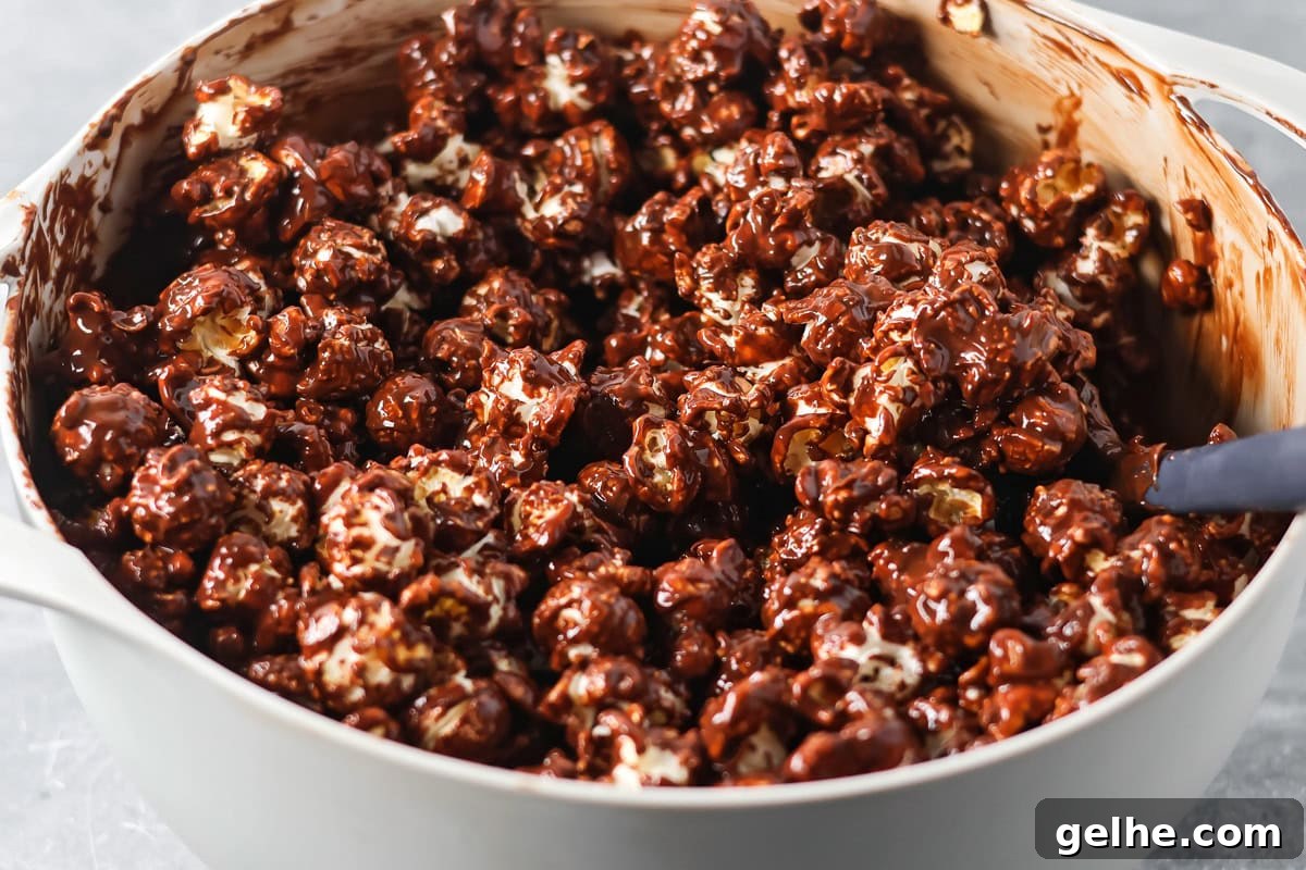 Puppy Chow Popcorn is an irresistible sweet and salty snack that's easy to make and guaranteed to be a hit. A bowl of popcorn coating in a chocolate peanut butter sauce.