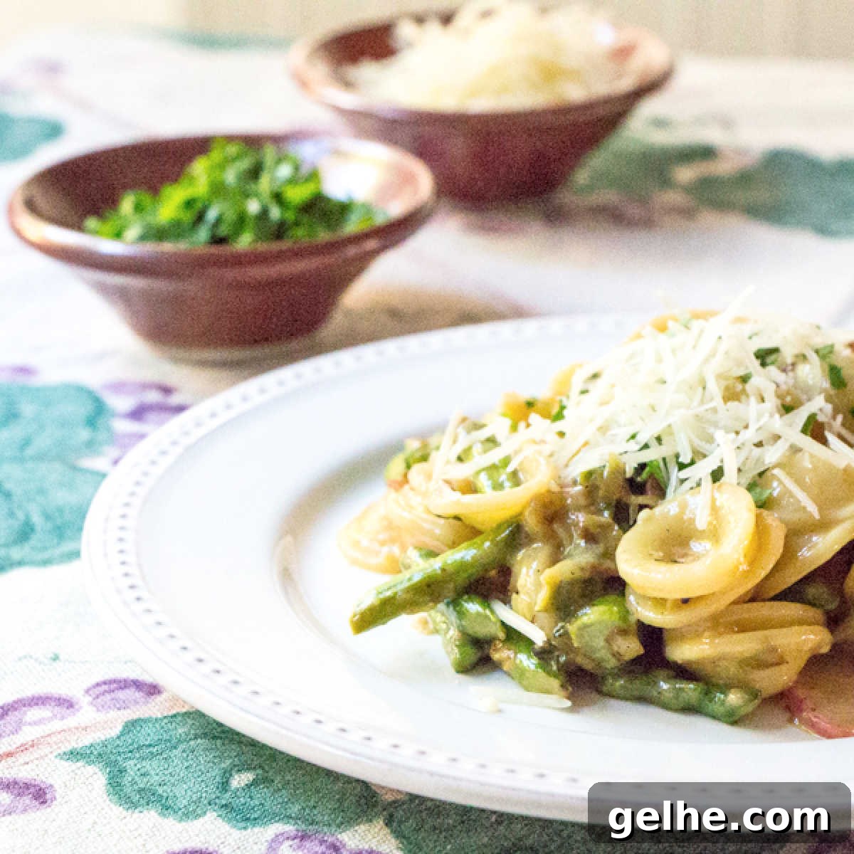 17 Delicious Vegetarian Easter Dinner Ideas for a Memorable Feast 15 A plate of asparagus carbonara with orcchiette pasta, with Parmesan and parsley in the background.