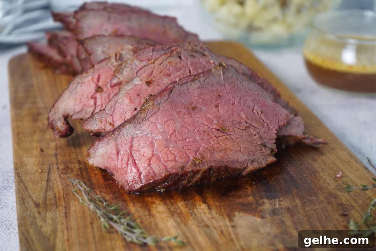 Smoked rump roast sliced with au jus behind and fresh thyme sprigs around it.