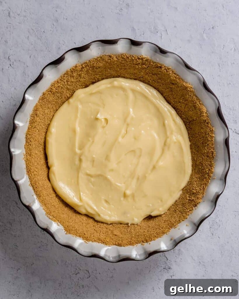top view of a pie graham cracker crust with a layer of vanilla pudding