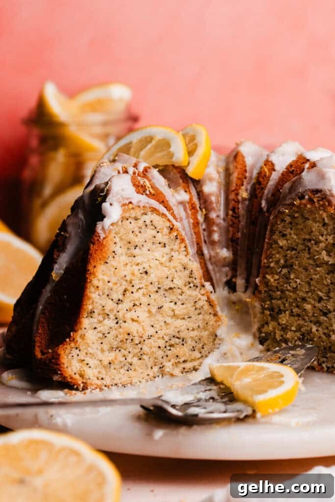 Moist Lemon Poppy Seed Bundt Cake Recipe with Zesty Glaze 2 The sliced cake on a marble cake plate. The fluffy and tender inside of the cake is visible.