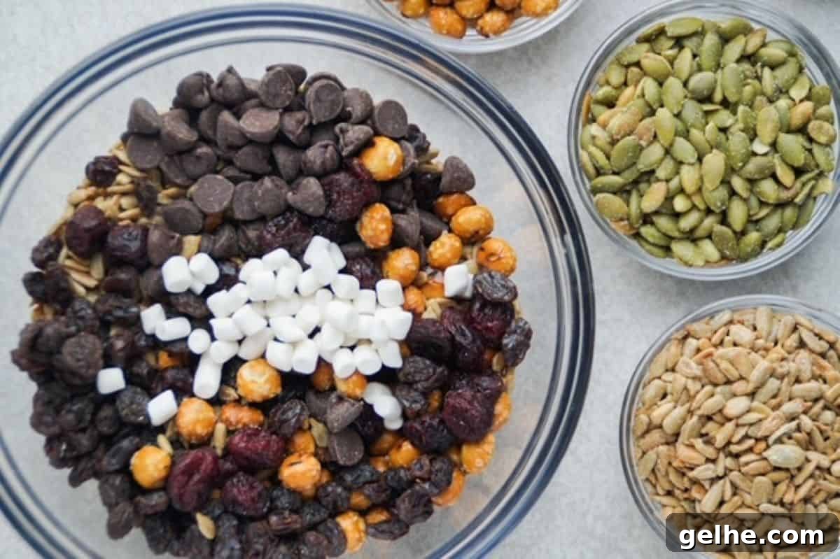 Nut free trail mix ingredients in a glass mixing bowl with small glass bowls of pumpkin and sunflower seeds to the right of it.