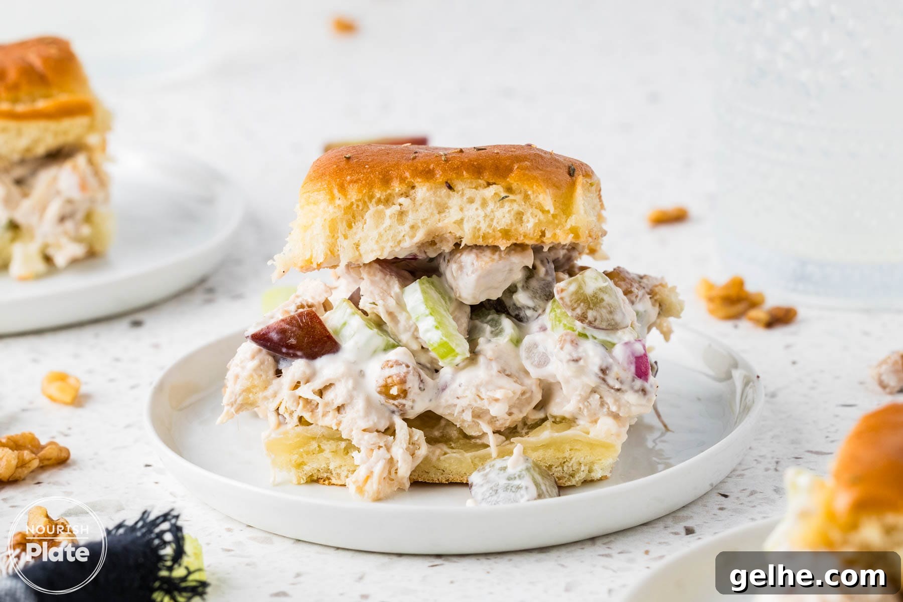Chicken salad slider with grapes, celery, walnuts, and creamy filling served on a white plate.