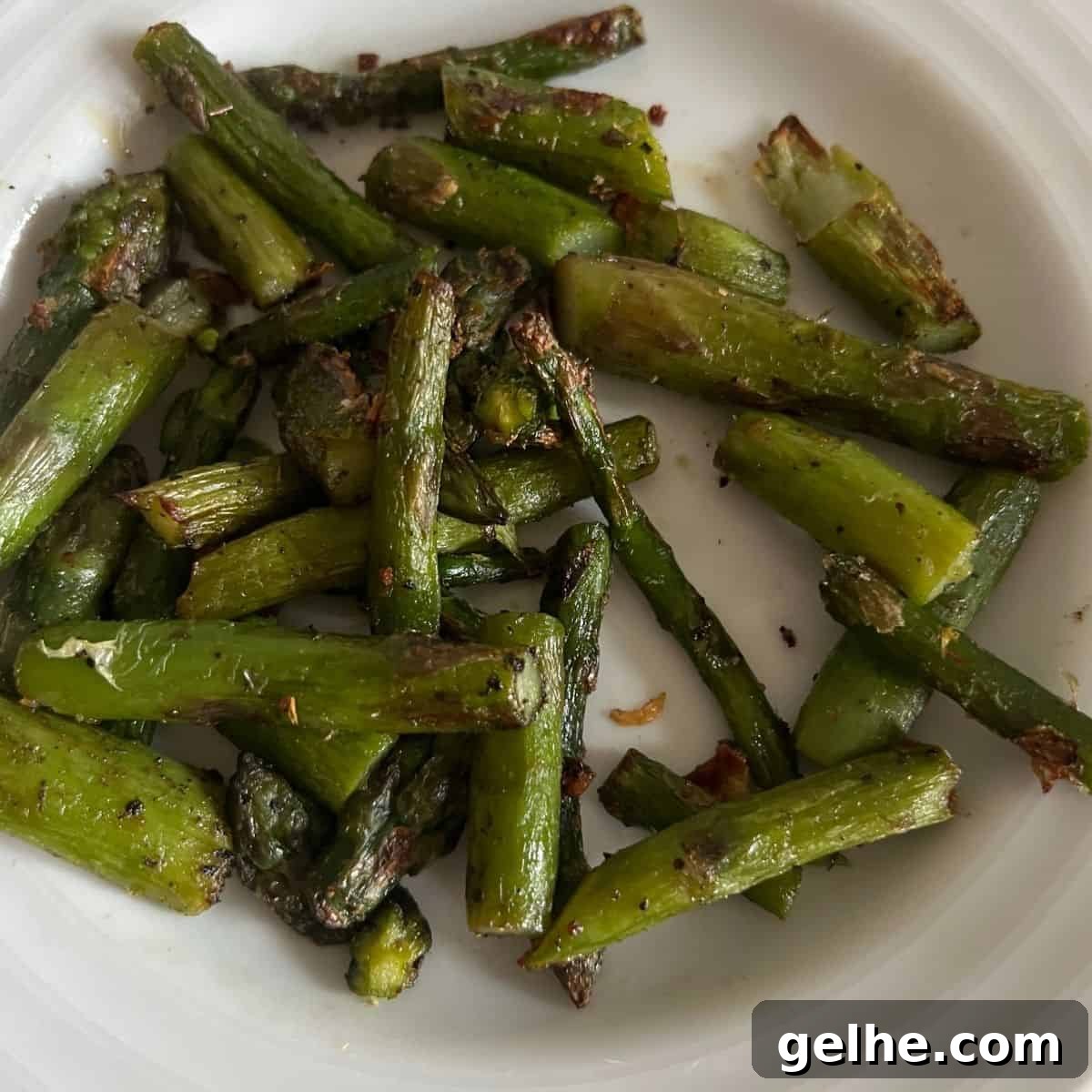 Air Fryer frozen cut asparagus on a white plate. 