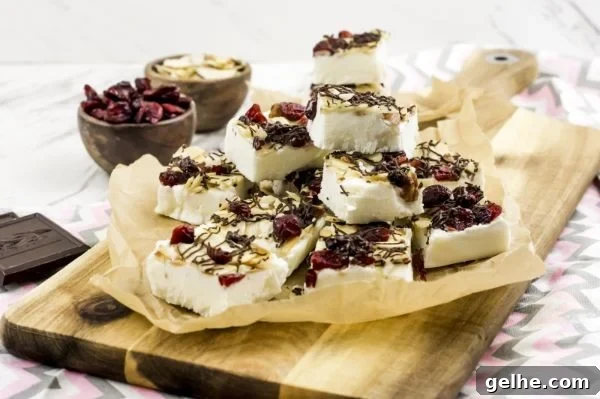 Toasted Almond Cranberry Bark Recipe with Step-by-Step Photos 5 WW Yogurt Bark finished and stacked on a sheet of parchment paper on top of a wooden cutting board.