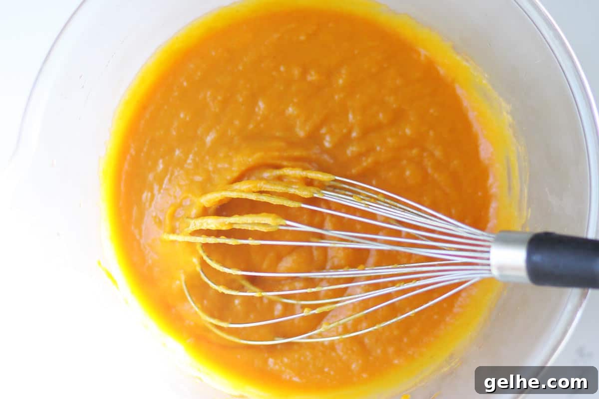 Chocolate Chip Pumpkin Muffins with Wholesome Ingredients 4 a mixture of pumpkin, coconut oil, honey and eggs in a bowl with a whisk in it