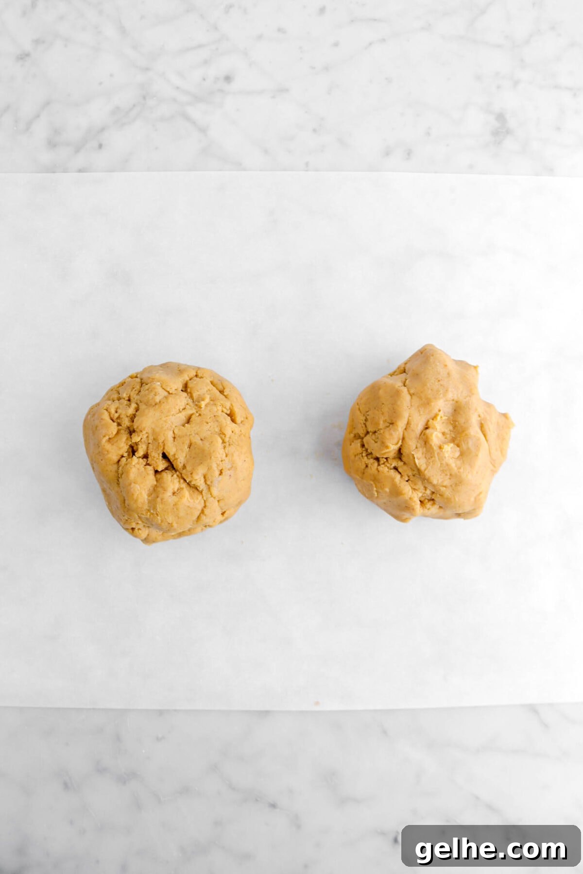 pumpkin cookie dough divided into two on parchment paper.