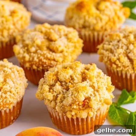 A platter of peach muffins topped with golden streusel crumble.