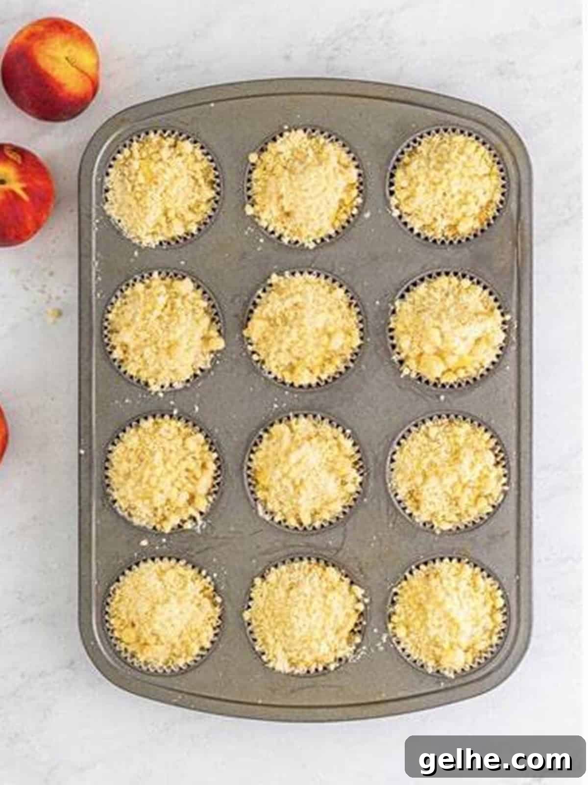Crumbly streusel topping added over the unbaked peach muffins.