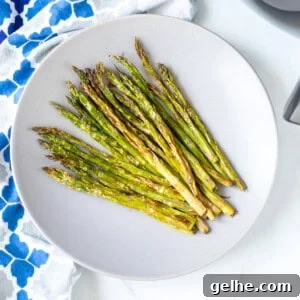 A plate of crispy asparagus next to air fryer.