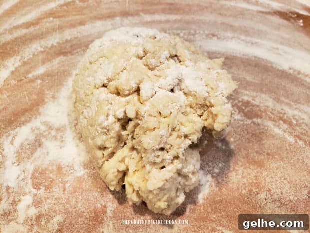 A shaggy ball of biscuit dough on a floured work surface before being flattened.