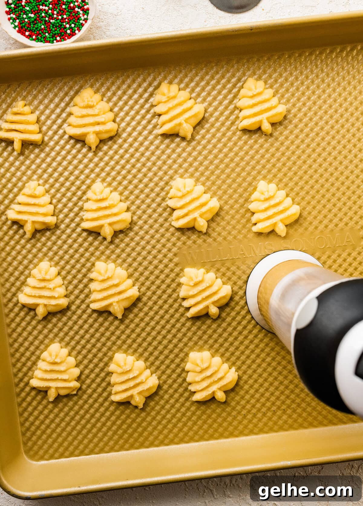 How to make Spritz cookies step-by-step: make shapes with the cookie press on the baking sheet.