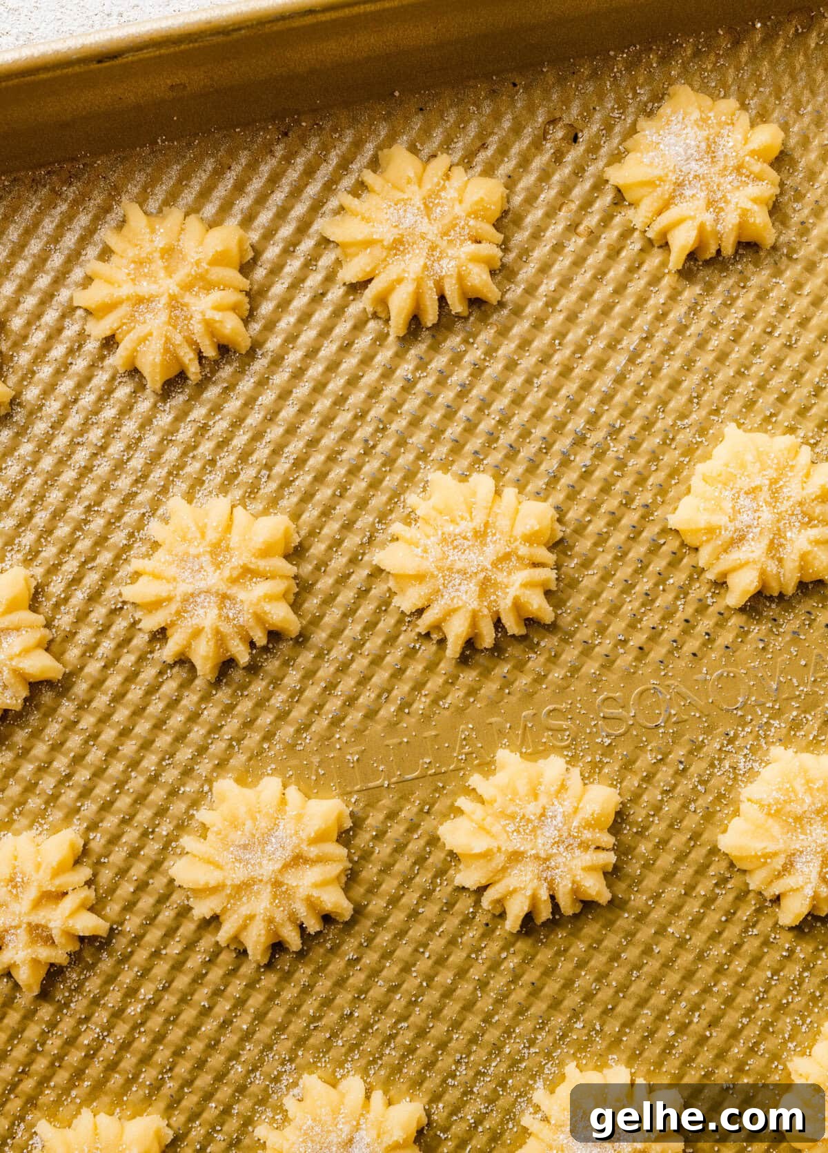 How to make Spritz cookies step-by-step: baked cookies on a baking sheet. Christmas snowflakes with white sprinkles.