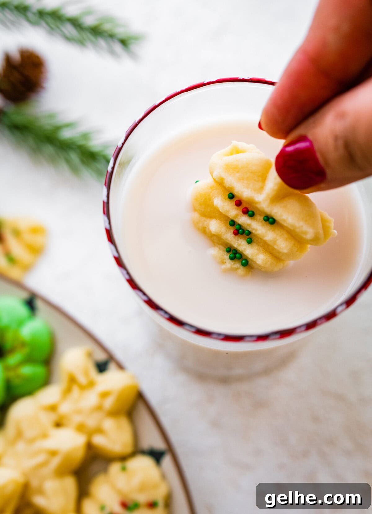 All the decorated spritz cookies on a beautiful festive cookie platter ready to serve. A glass of milk and a cookie.