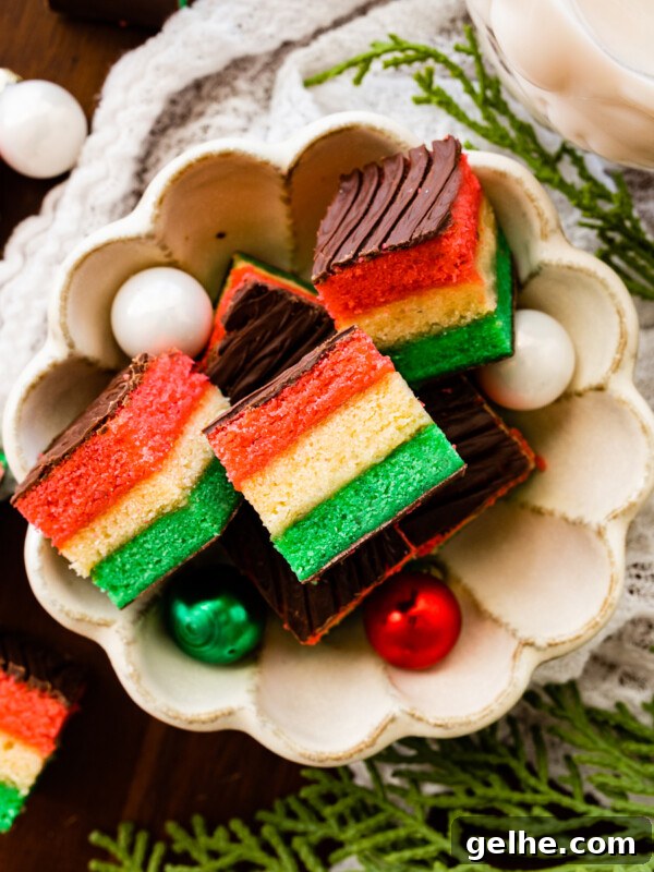 Italian rainbow cookies in a bowl with Christmas bulbs.
