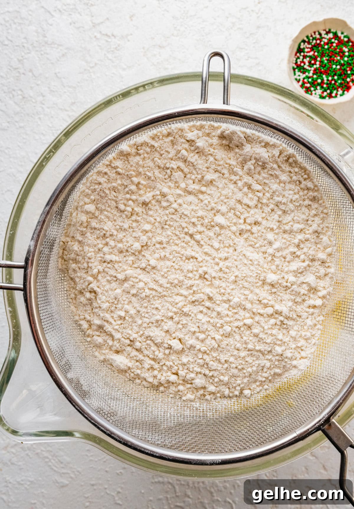 How to make Spritz cookies step-by-step: sift in the flour over the bowl of wet ingredients.