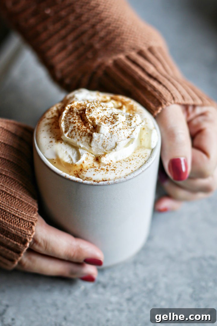 photo of woman holding a mug of pumpkin hot chocolate with vanilla whipped cream