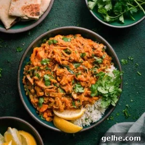 vegan jackfruit curry in green bowl with cilantro, lemon and naan on the side