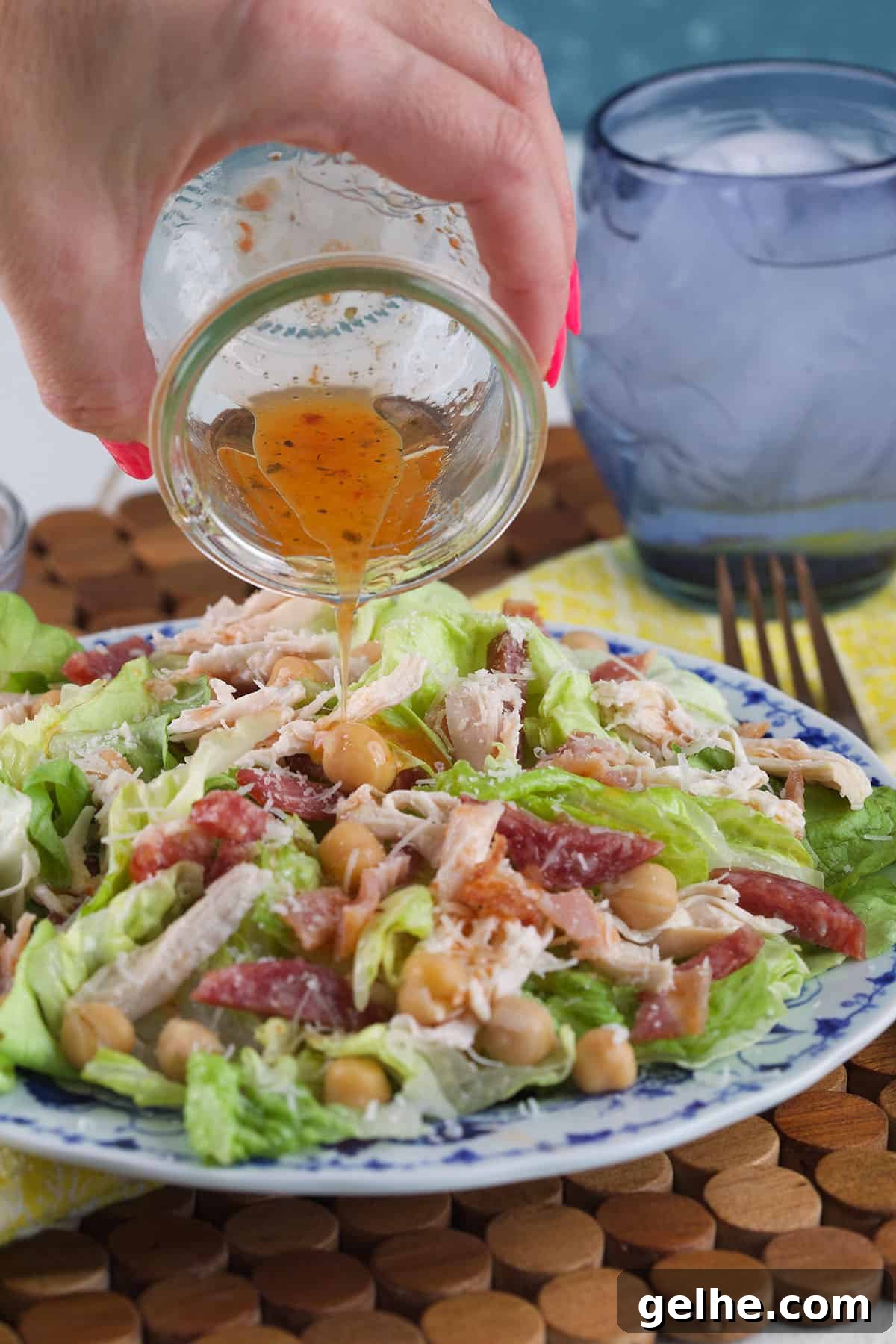 Dressing is being poured on top of a tossed salad.