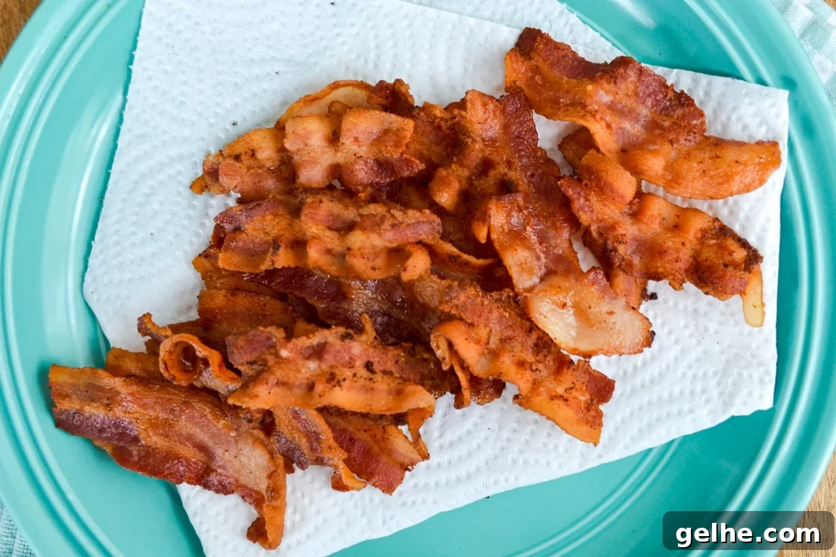 Cooked bacon slices on a paper towel lined plate.