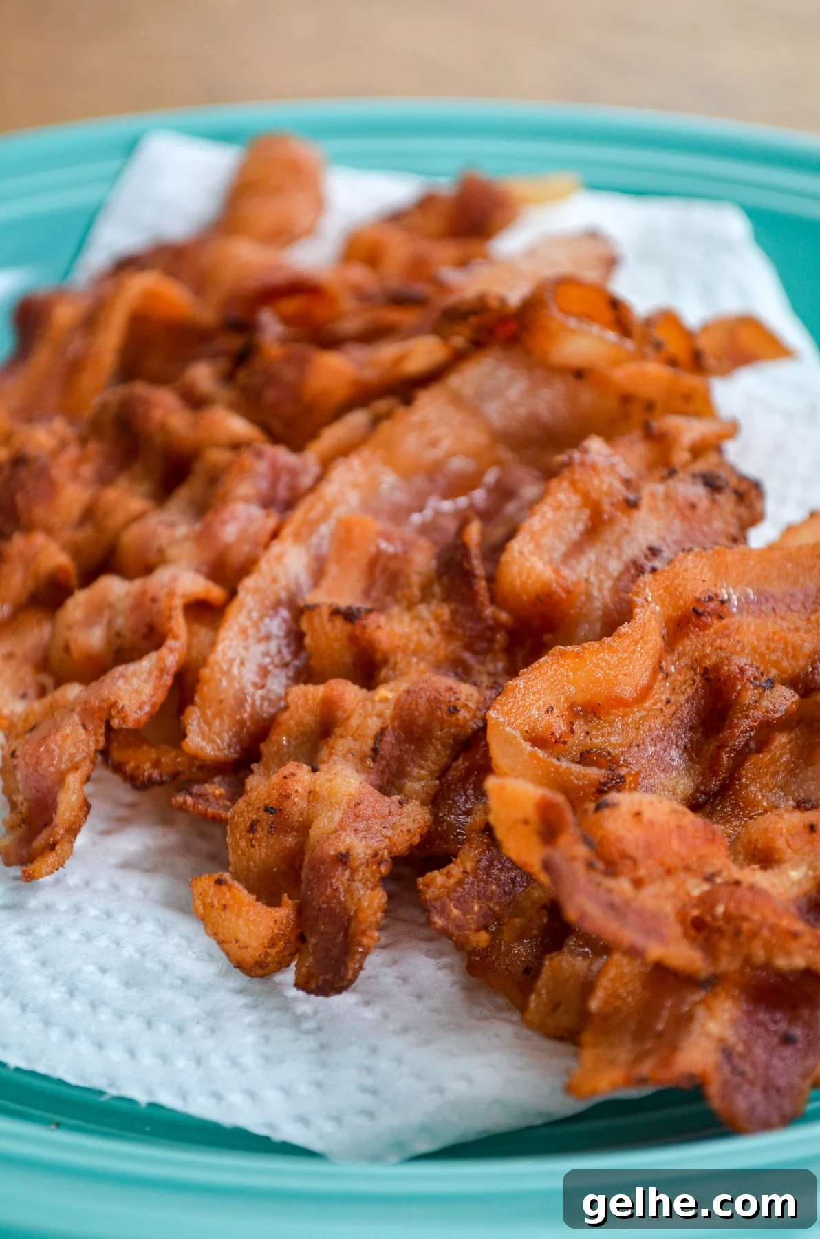 Instant Pot Bacon Slices, crispy and draining on a paper towel lined plate.