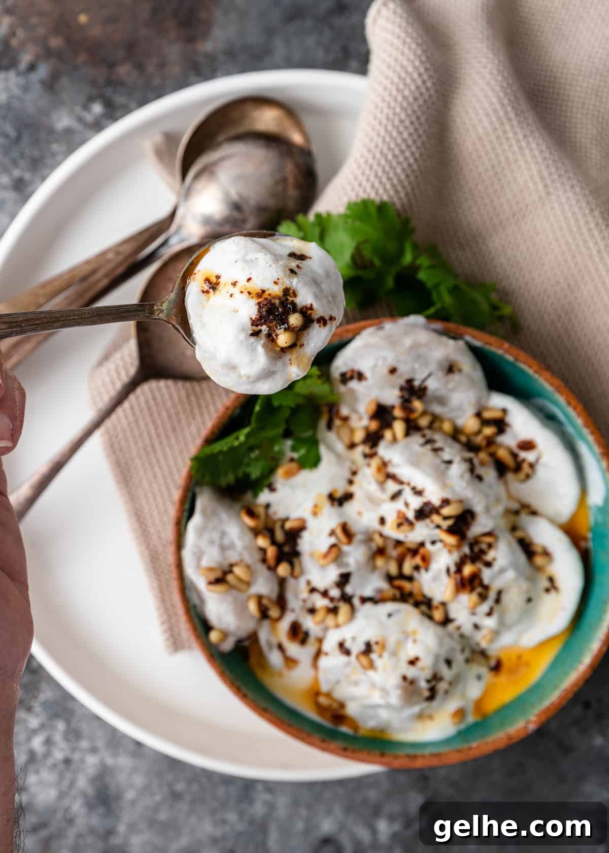 overhead lebanese meat dumpling in spoon with yogurt sauce