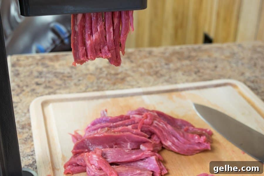 erky slicer slicing venison for jerky onto a cutting board with knife