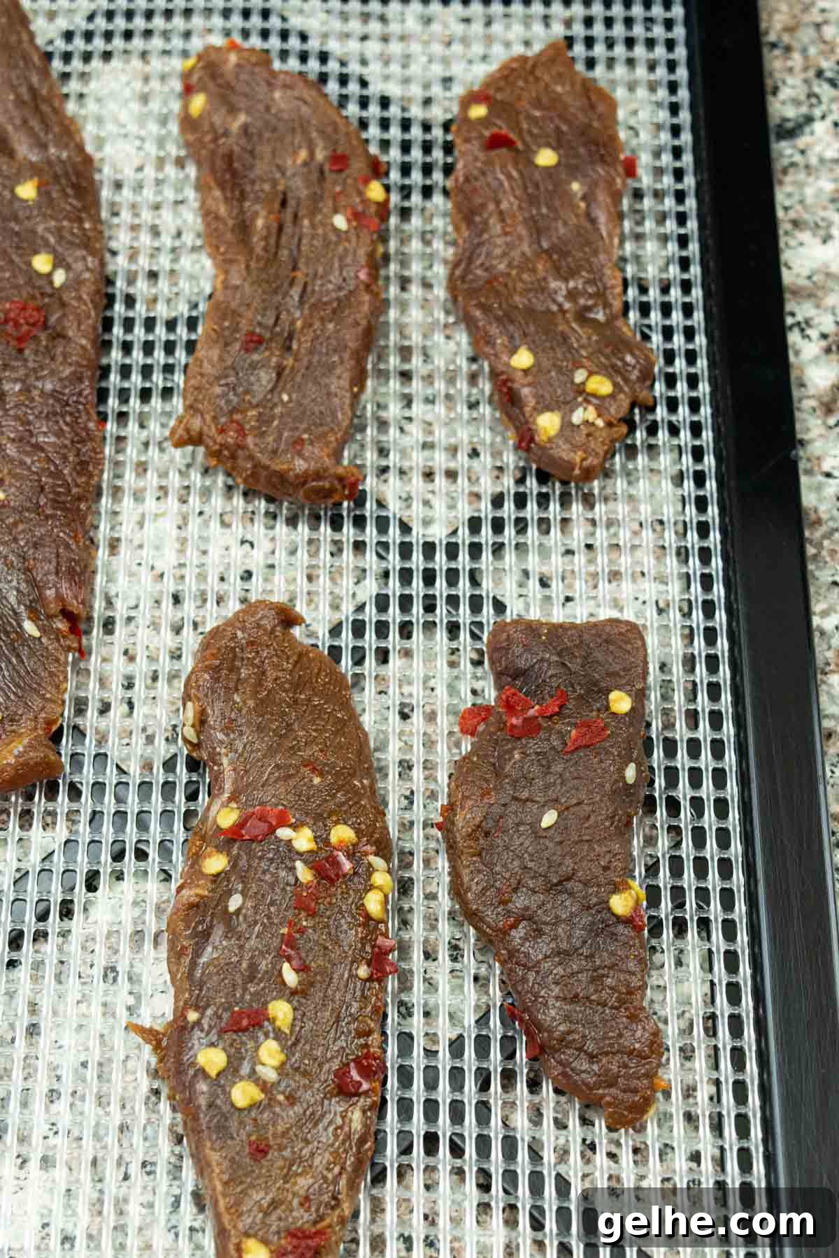venison jerky on dehydrator tray ready to be dehydrated into jerky