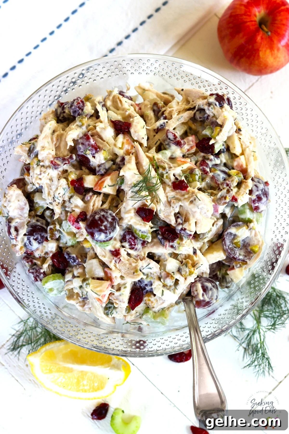 Rotisserie Chicken Salad Recipe for Quick Weeknight Meals 2 A round clear bowl served with chicken salad and garnished with cranberries and dill.