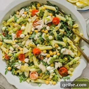 Chicken pesto pasta salad tossed on a scalloped white bowl.