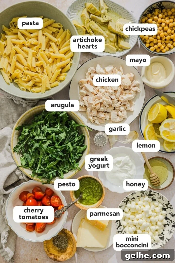Ingredients for pesto chicken pasta salad displayed in small bowls on a marble counter.