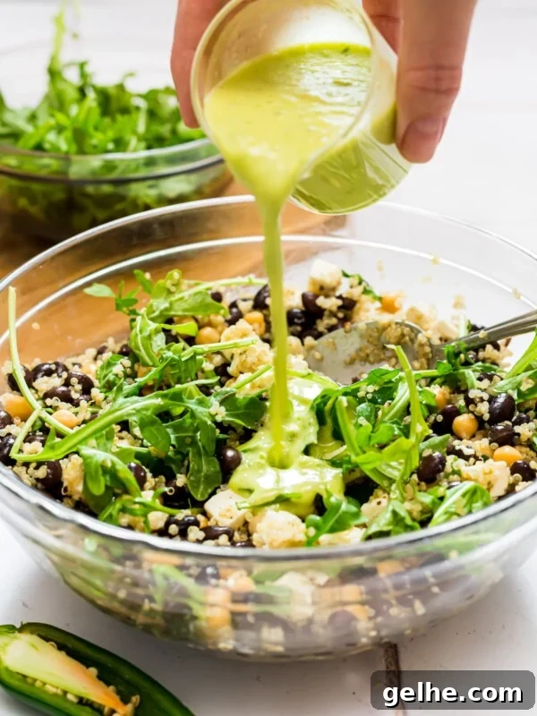 Quinoa and arugula salad with honey jalapeno green dressing being poured over