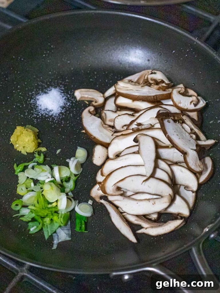 sliced shiitake mushrooms in a pan with scallions and garlic