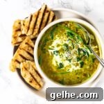 Aa top down view of a bowl of curried lentil soup with grilled naan bread on the side.