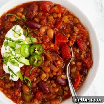 a bowl of vegetarian chili with lentils on a table ready to eat