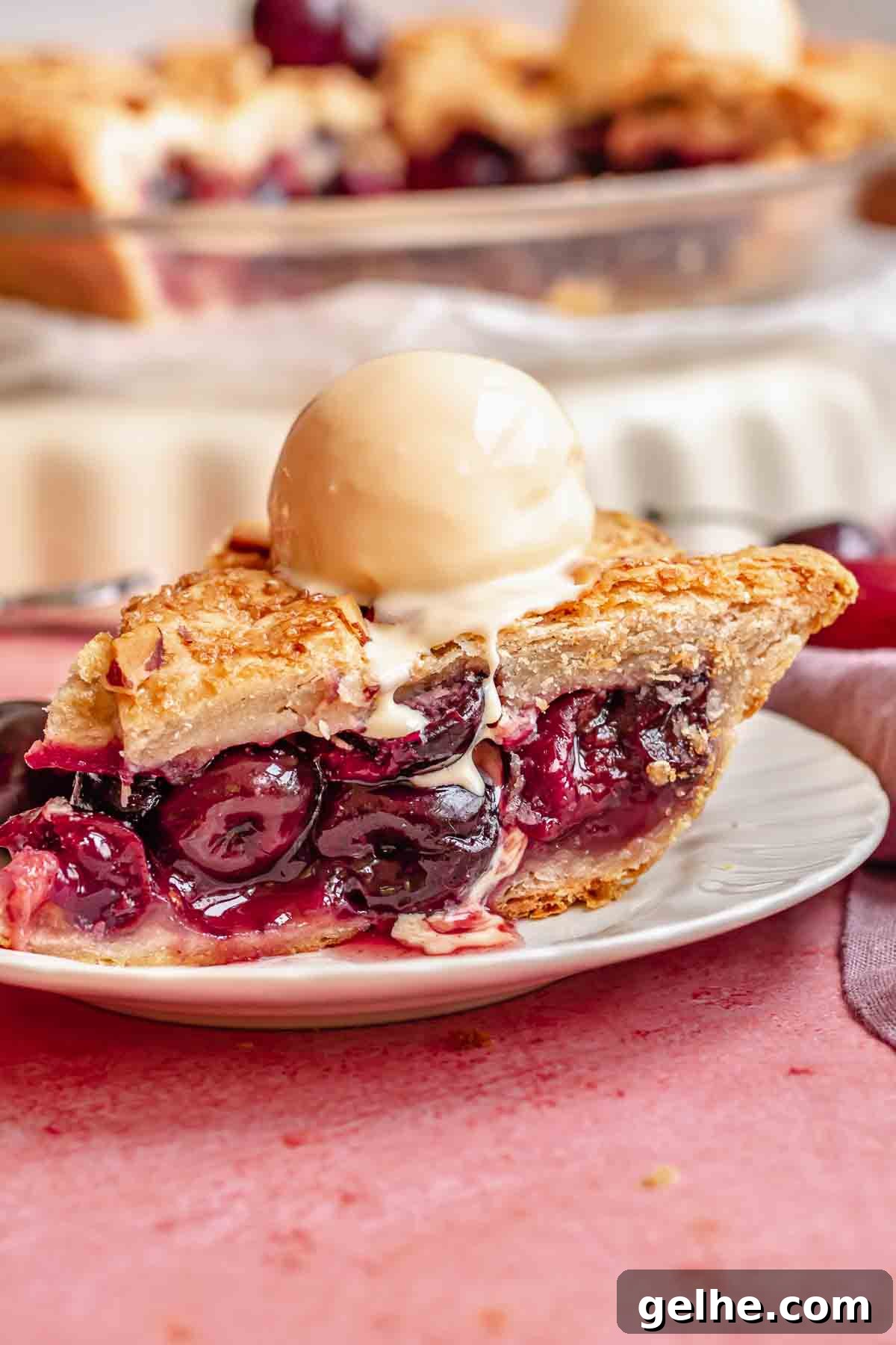 Cherry Rhubarb Pie Recipe: Sweet-Tart Homemade Dessert 2 A slice of cherry rhubarb pie on a plate with a scoop of ice cream on top.