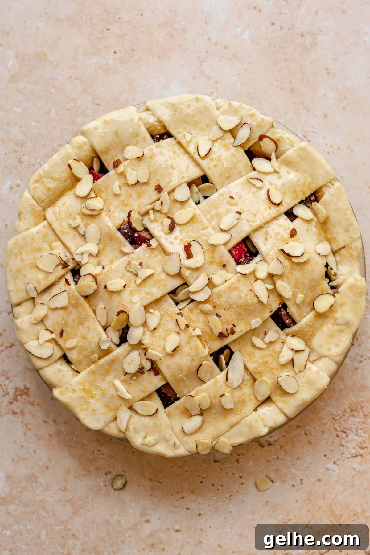 Cherry Rhubarb Pie Recipe: Sweet-Tart Homemade Dessert 15 Pre-baked cherry rhubarb pie with coarse sugar and sliced almonds on top.
