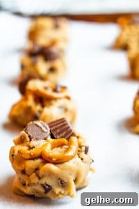 Peanut butter cookie dough on a cookie sheet in a line.