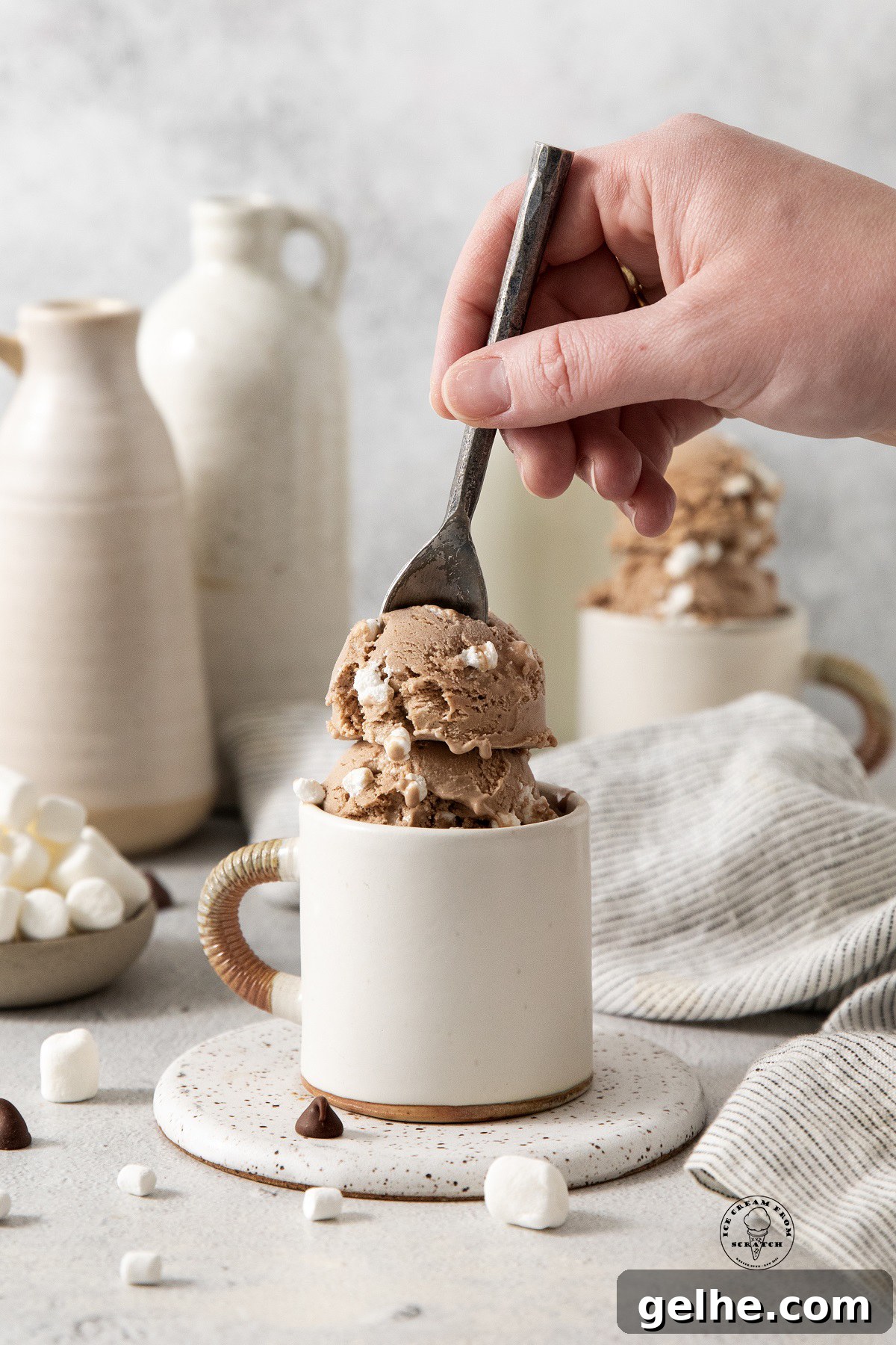 Homemade Hot Chocolate Ice Cream Recipe for Rich, Chocolatey Flavor 5 a hand holding a spoon, eating hot chocolate ice cream from a white ceramic mug.