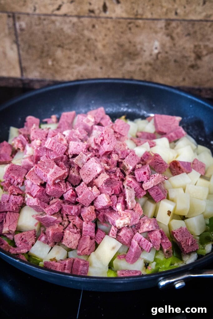 Make homemade corned beef hash with leftover corned beef, tender potatoes, onions, and bell peppers. An easy breakfast, ready in 30 minutes! Chopped corned beef added to a skillet with diced sauteed onions and peppers.