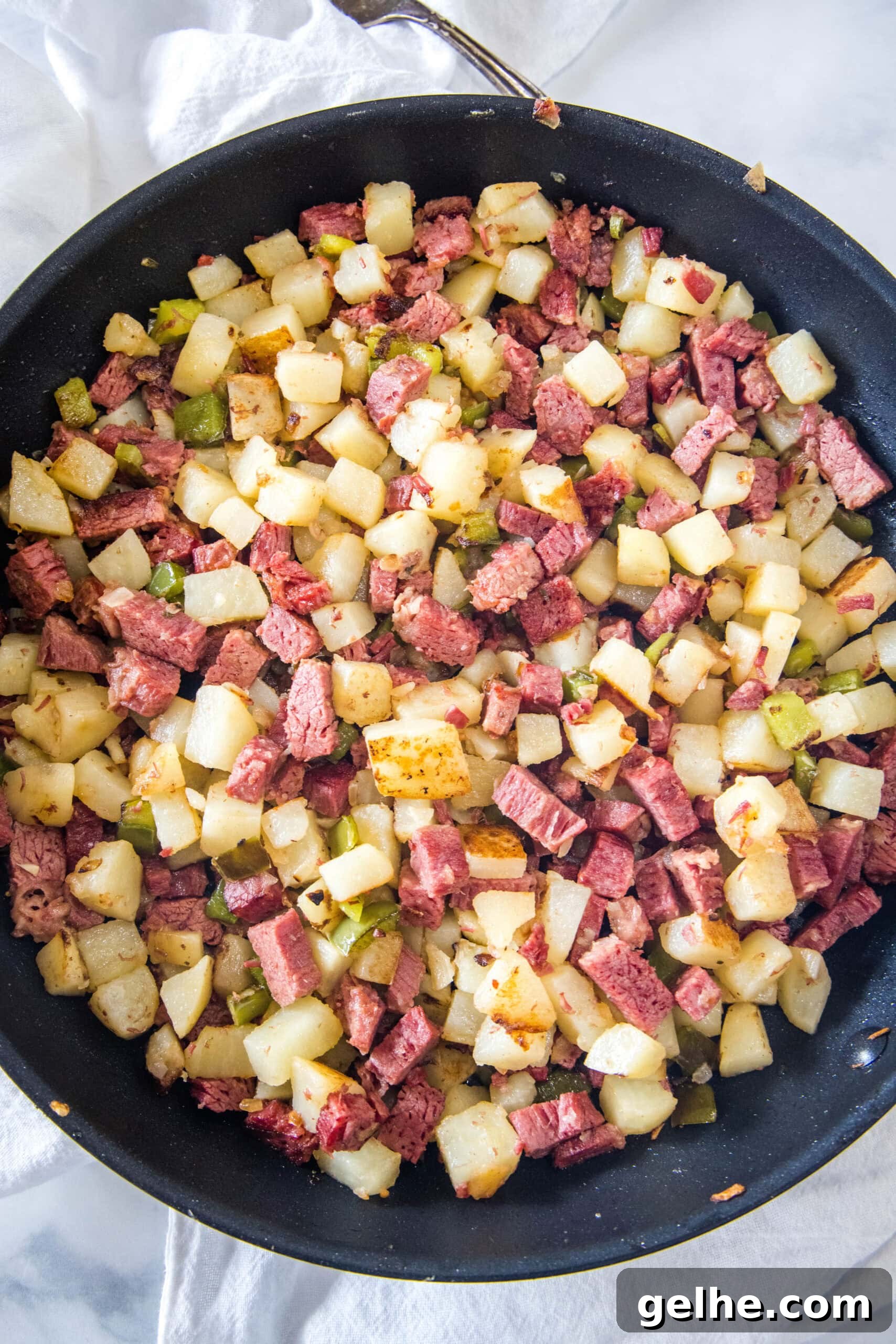 Make homemade corned beef hash with leftover corned beef, tender potatoes, onions, and bell peppers. An easy breakfast, ready in 30 minutes! Overhead view of diced potatoes, chopped corned beef, onions, and bell peppers combined in a skillet for corned beef hash.