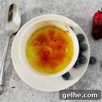 Crème Brûlée in the Instant Pot: Silky Custard with Caramelized Top 2 Baked custard in a white bowl with caramel topping and blueberries on the side.