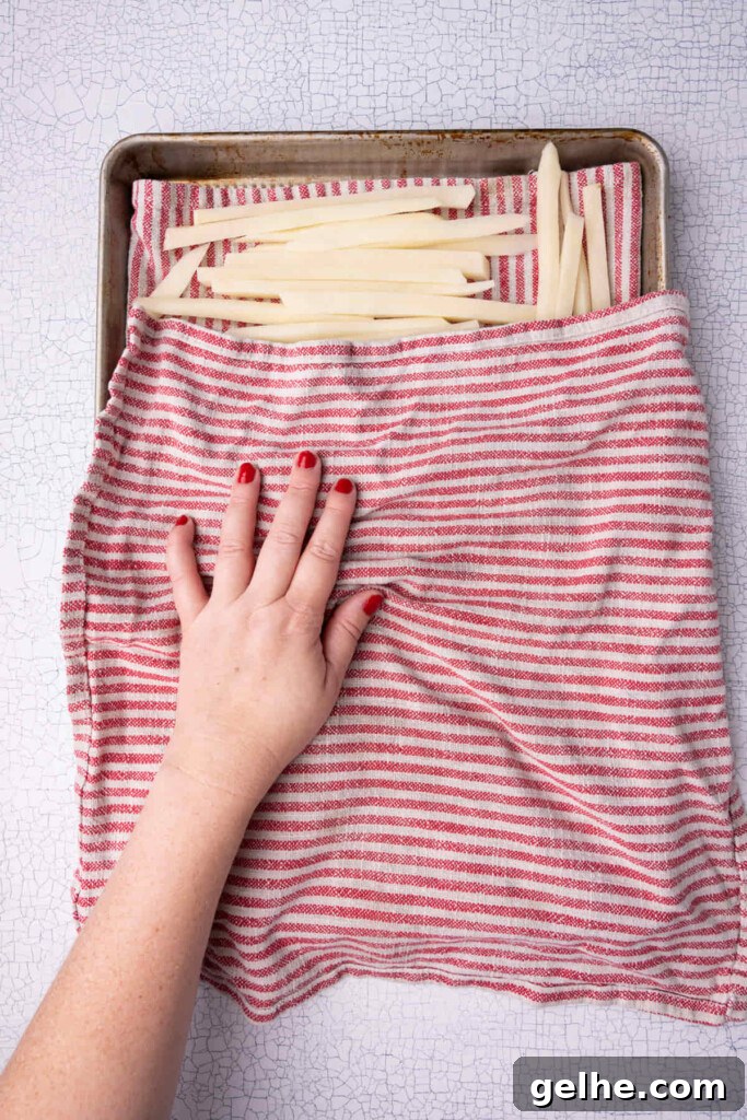 Crispy Cajun Fries: Oven or Air Fryer Recipe for Perfect Seasoning 7 Drying off fries that have been soaked in water before baking to crispy perfection.