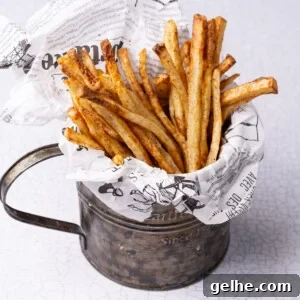 Crispy Cajun Fries: Oven or Air Fryer Recipe for Perfect Seasoning 9 Cajun fries served up in a large cup with parchment paper.