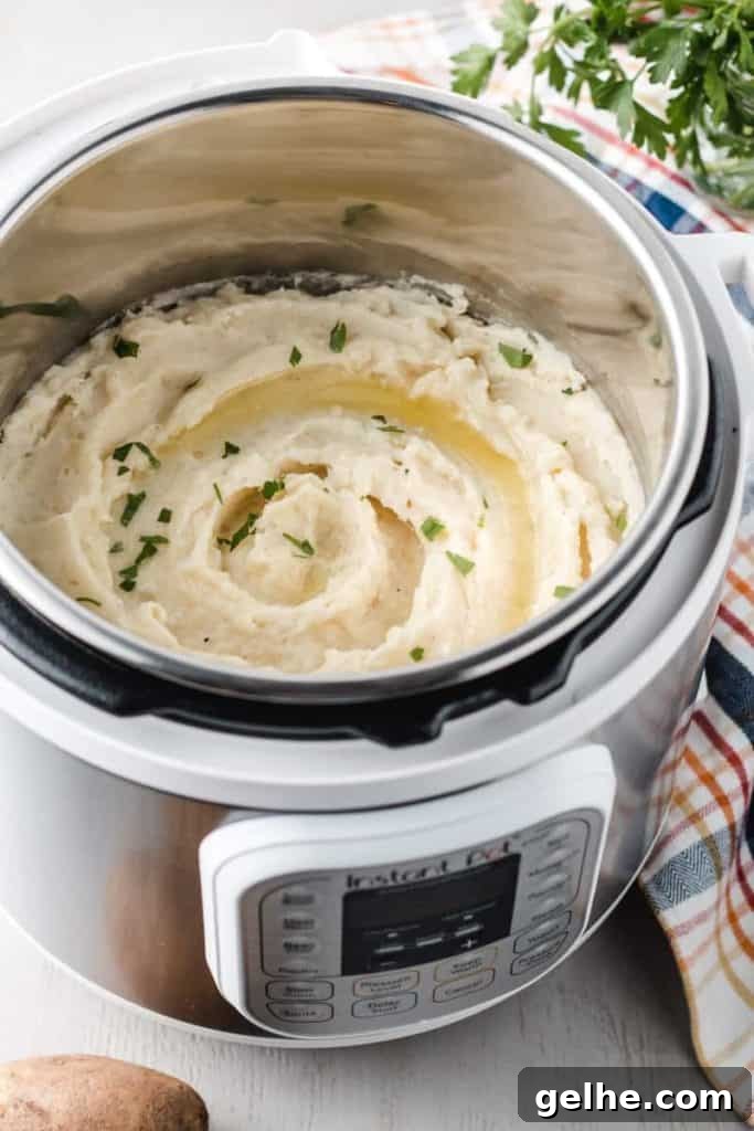 Instant Pot Mashed Potatoes in 20 Minutes 2 A white instant pot full of mashed potatoes with butter and parsley on top.