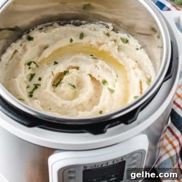 Instant Pot Mashed Potatoes in 20 Minutes 6 A white instant pot full of mashed potatoes with butter and parsley on top.