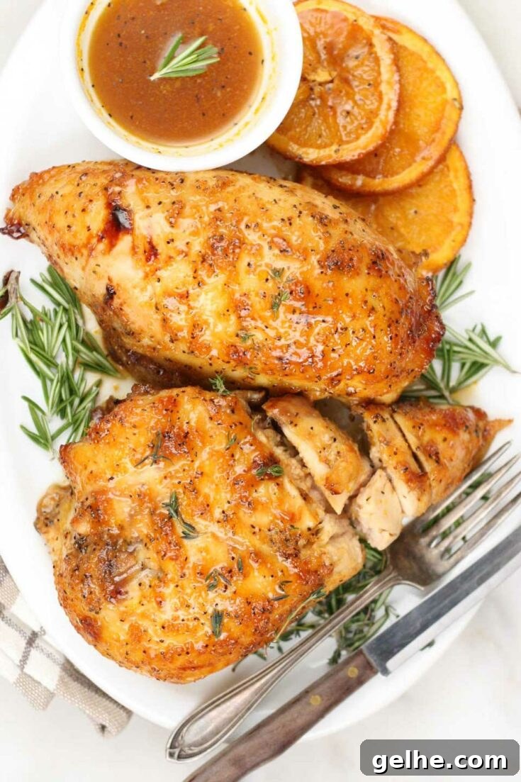 Orange glazed chicken on platter with oranges and rosemary.