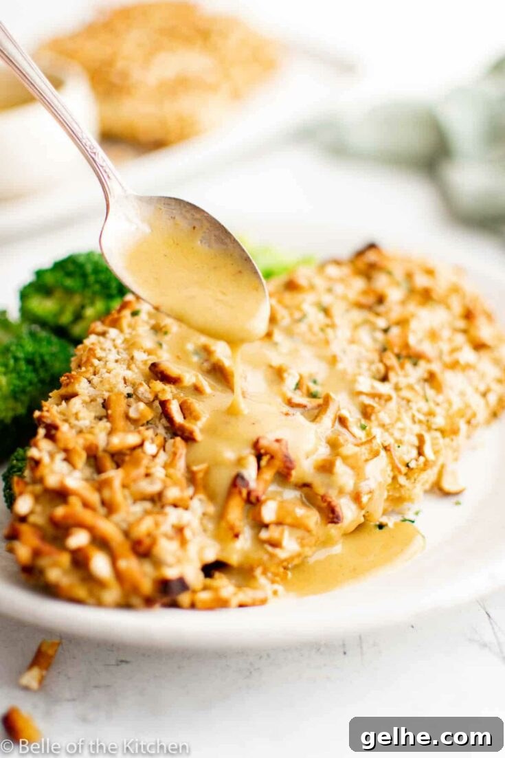 Pretzel crusted chicken on white plate with broccoli.