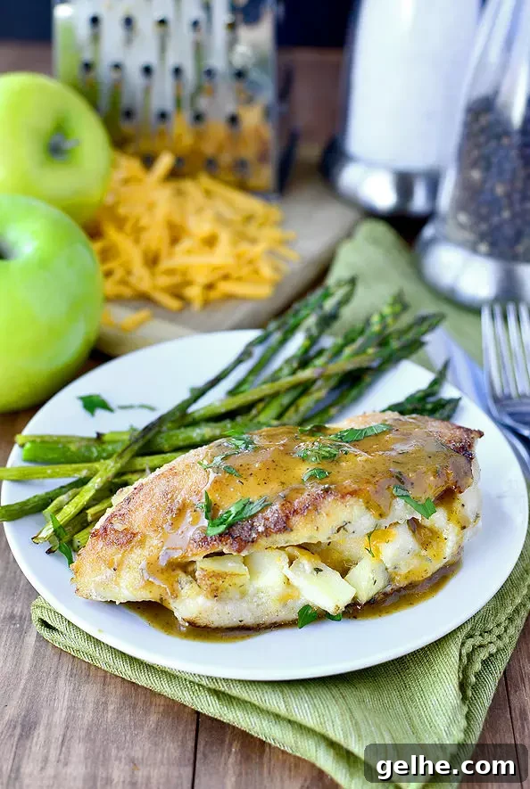 Apple-cheddar stuffed chicken with asparagus on plate.
